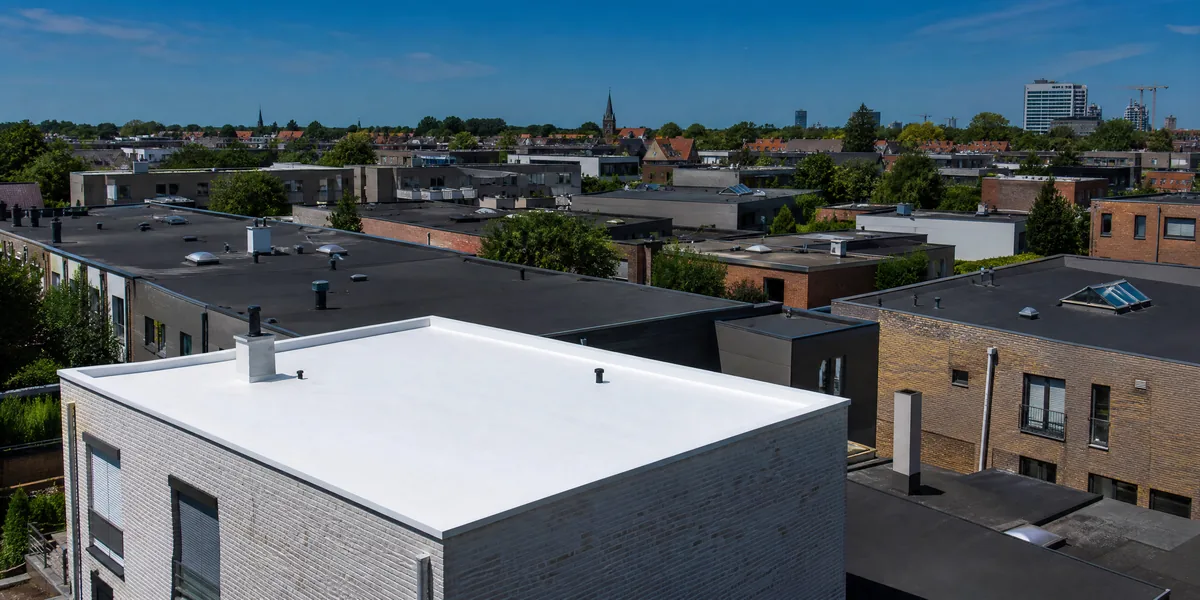 Toiture plate blanche réfléchissante contrastant avec les toits sombres voisins